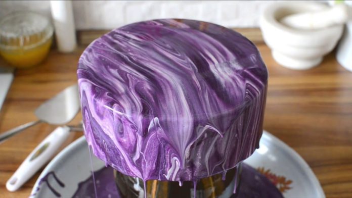 Elle commence à verser un glaçage violet sur le gâteau : le résultat est... brillant!