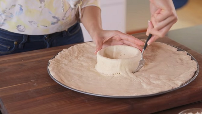 Elle étend la pâte à pizza, en créant un trou au milieu. L’idée est vraiment délicieuse!