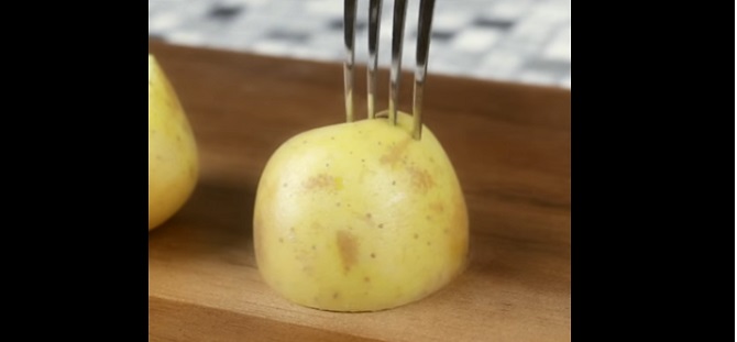 Il embroche une demi-pomme de terre avec une fourchette: Voici une astuce utile pour le barbecue!